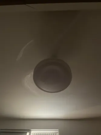 Ventilador de techo blanco girando con la luz apagada en un dormitorio